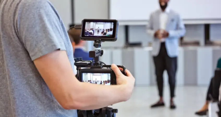 A man holding a video camera captured a group of people in a Professional Video Production Company 